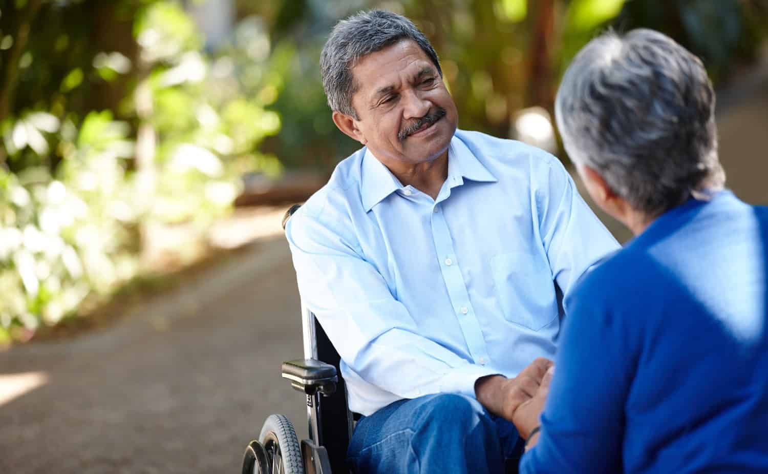 senior man in wheelchair outside talking to nurse