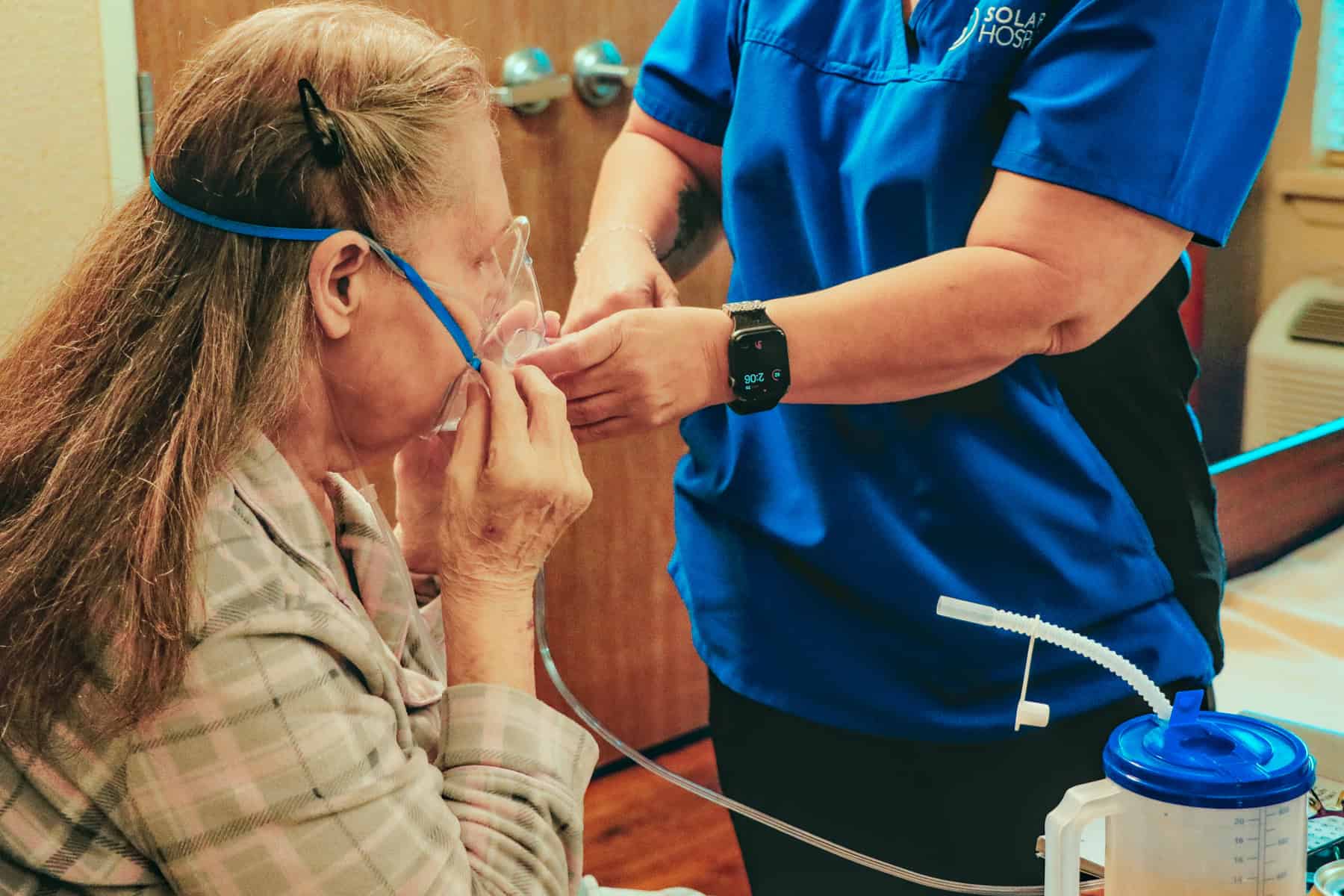 Senior woman receiving oxygen therapy from healthcare professional at Solaris Healthcare.